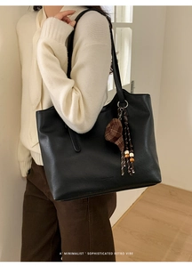 Detail of black faux leather tote bag with unique plaid hat pendant and wooden bead tassel