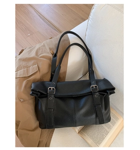 Detail of black pebbled leather texture and silver buckle on large tote bag