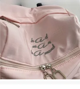 Détail du tissu en nylon rose imperméable avec double zip argenté et broderie élégante