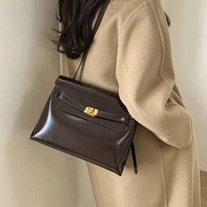 Detail of the vintage dark brown leather bag showing the golden twist lock and smooth texture