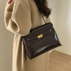 Detailed view of dark brown glossy leather texture and gold twist lock on the handbag