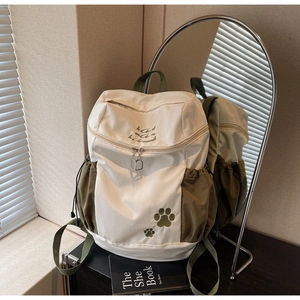 Détail du sac à dos en toile blanc et olive avec broderie et motifs de pattes vertes
