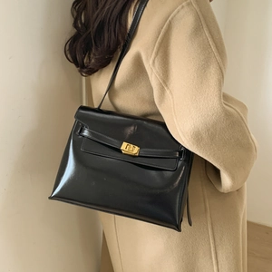 Detailed side view of a black leather crossbody bag featuring a golden rotating lock