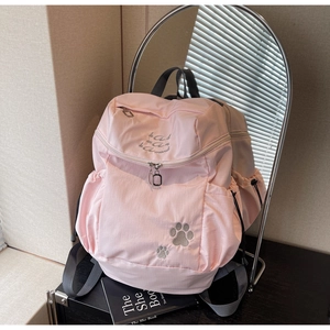 Détail d'un sac à dos rose clair avec broderie patte de chat et fermetures éclair robustes