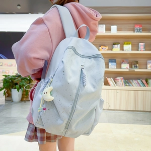 Close-up of light blue backpack with silver stars, dual zippers and moon plush charm