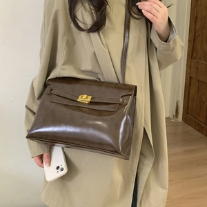 Close-up of a deep brown faux leather tote bag with a gold metal clasp and adjustable strap