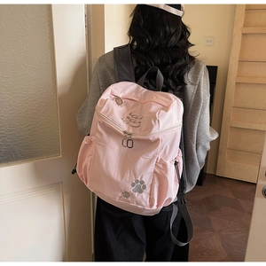 Gros plan du sac à dos rose avec broderie de patte de chat et poche latérale à cordon