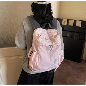 Détail du sac à dos rose en nylon avec poches latérales à cordon et bretelles grises