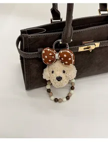 Gros plan d'un charme chiot en peluche avec perles sur un sac à main vintage marron