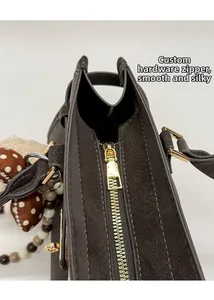 Détail de la fermeture éclair dorée et des coutures sur un sac Boston marron