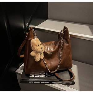 Detailed view of vintage brown tote bag featuring a gold chain and cute bear charm pendant