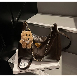 Detail of dark brown tote bag texture with golden chain and plush dog charm
