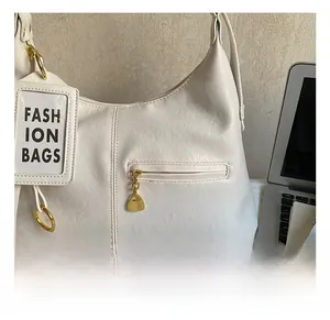 Close-up of white leather tote bag featuring gold zipper hardware and vertical stitching
