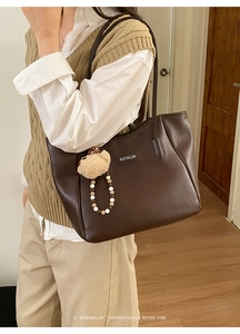 Détail du sac cabas vintage en cuir marron foncé avec breloque ours et chaîne de perles
