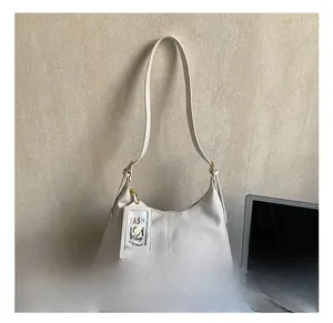 White minimalist hobo shoulder bag featuring a leather strap and gold hardware accents