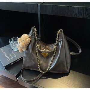 Detail of dark brown hobo bag with golden triangle logo and plush bear charm