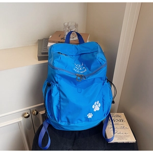 Détail d'un sac à dos en nylon bleu avec broderie blanche et motifs de pattes de chat