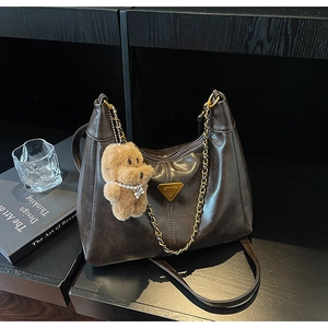 Detailed view of coffee brown retro shoulder bag with gold chain and plush bear charm