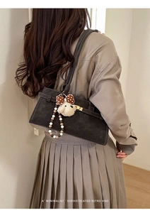 Détail du sac à bandoulière rétro gris foncé avec fermoir doré et accessoire de chien