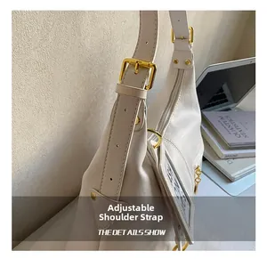 Detail of adjustable shoulder strap with gold buckle on cream faux leather tote bag