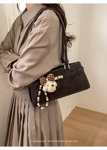 Détail du sac rétro marron foncé avec boucle métallique et breloque en peluche