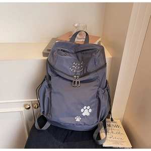 Détail du sac à dos gris à carreaux avec broderie pattes d'animaux et poche latérale