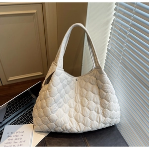 Close-up of quilted tote bag details with metal snap closure and soft puffy texture