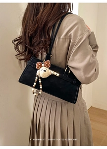 Détail du sac rétro noir avec fermoir métallique et breloque caniche élégante