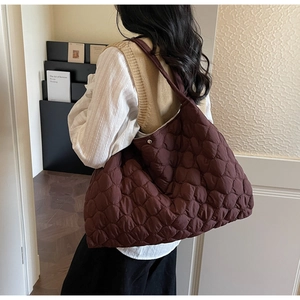 Detail of the large quilted tote bag with metallic snap closure in deep burgundy