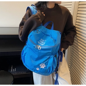 Gros plan du sac à dos bleu en nylon imperméable avec broderie de pattes de chat blanches