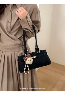Détail du sac rétro en daim noir avec fermoir doré et pendentif ours en peluche