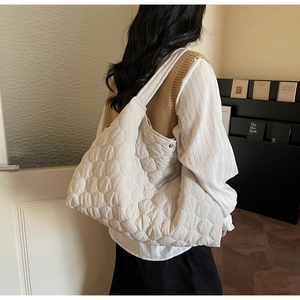 Detail showing wavy quilted texture and soft fabric of the cream tote bag on shoulder