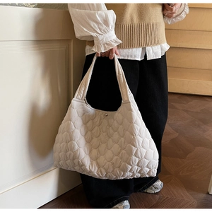 Close-up of beige quilted tote bag showing diamond stitch patterns and soft puffer texture