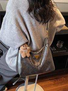Vintage leather hobo shoulder bag with metal logo and cute bear charm in indoor setting