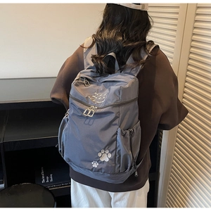 Détail de la broderie patte de chat et texture en nylon sur le sac à dos gris