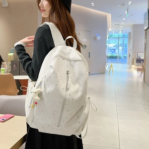 White minimalist star print backpack with plush moon charm shown on a female model