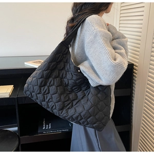 Detail of black quilted puffer tote bag with semi-circular stitching on soft nylon fabric