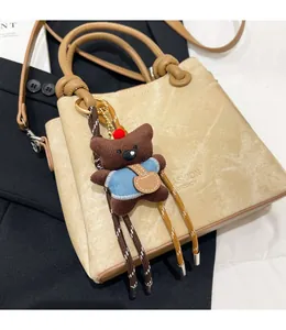 Detail of beige leather handbag with teddy bear charm and Fashion Gfancy logo text