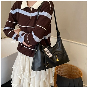 Black crescent shoulder bag with glossy finish and gold hardware shown on a model