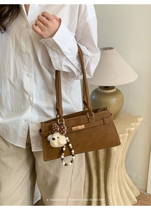 Détail d'un sac à bandoulière en simili daim marron avec boucle dorée et petit ours