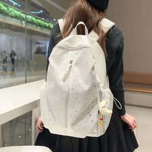 Close-up of white backpack with grey stars featuring vertical zipper and plush moon charm