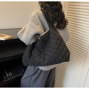 Close-up of black quilted puffer tote bag with soft fabric texture and arched stitching