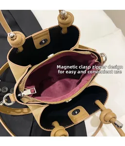Close-up of triple compartment layout with magnetic buckle and zipper on tan bucket bag