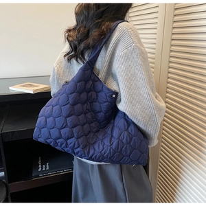 Detail showing navy blue quilted puffer tote bag with diamond pattern and wide strap