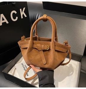 Detail van bruine suède tote bag met ruitstiksel in een zwarte geschenkdoos