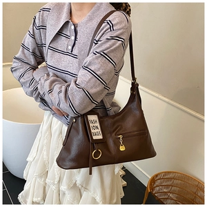 Detail of vintage brown leather tote bag featuring decorative zipper and metallic ring