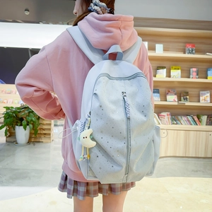 Detail of light blue school backpack with silver star prints and plush crescent charm