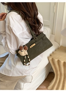 Détail du sac à bandoulière rétro vert olive avec boucle dorée et breloque en peluche