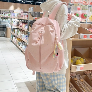 Pink star-patterned backpack featuring a front zipper and plush keychain accessory