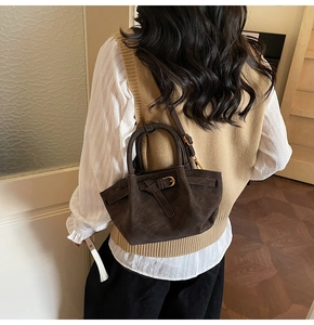 Vue arrière d'un mannequin portant un sac seau marron foncé matelassé avec une boucle élégante